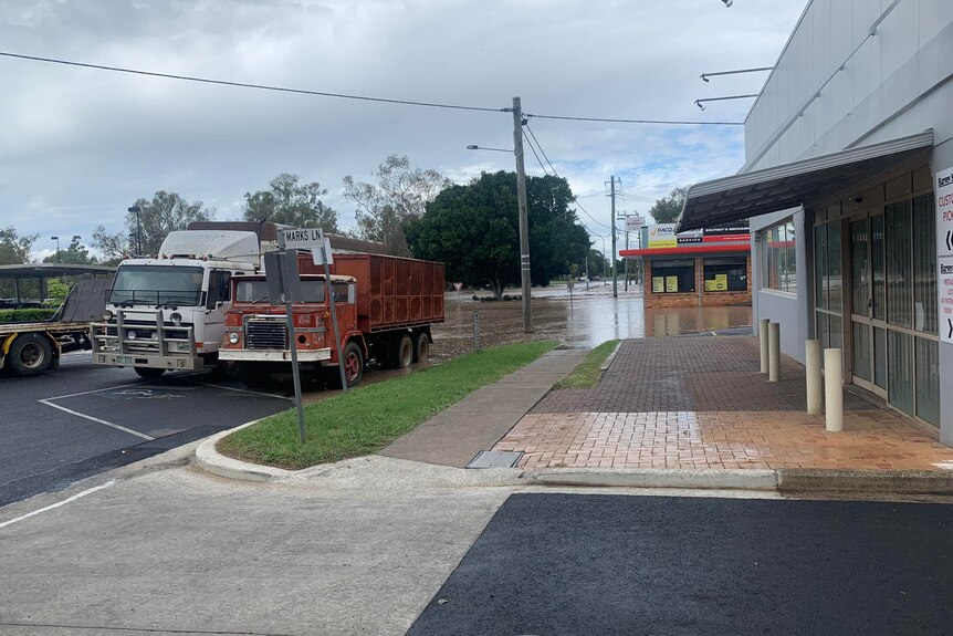 Flood water covers an entire street in Dalby. Water reaches up the tires of two trucks. 