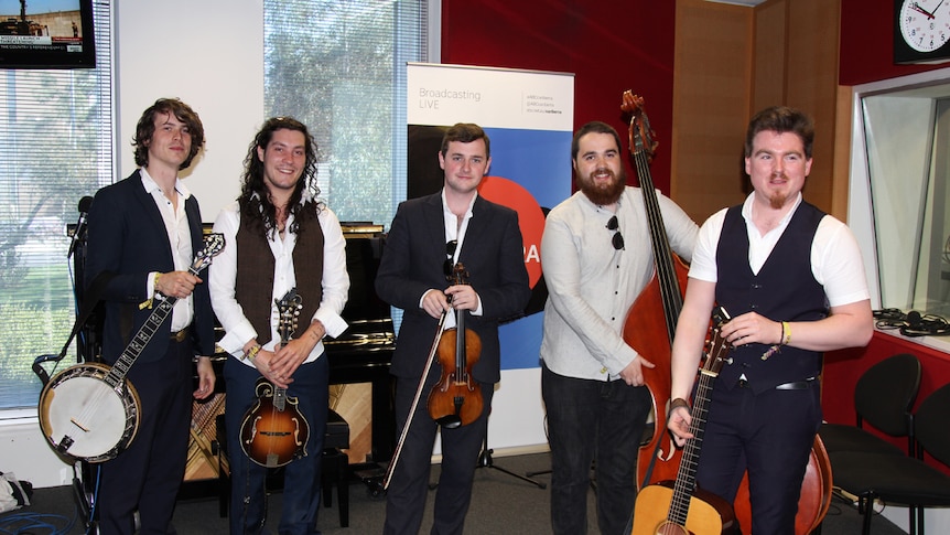 Band members with long hair holding a guitar, mandolin, and various instruments