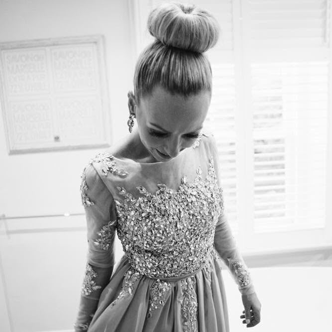 A black and white photo of a woman looking down wearing a sequined dress.