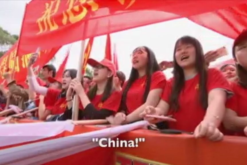 A crowd of Chinese students behind a barrier at a protest.