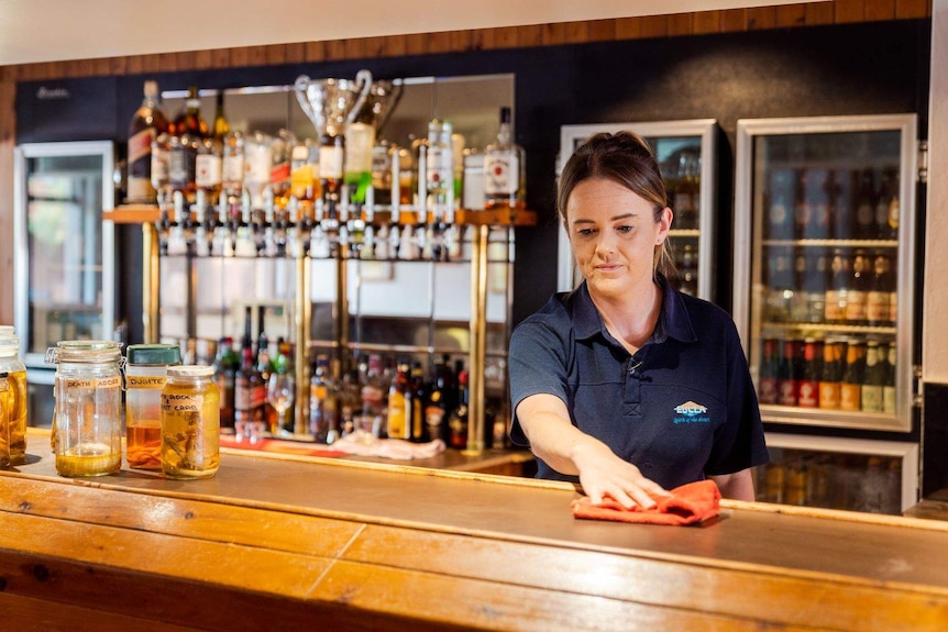 Brooke Littlewood wiping down a counter in a bar at the Eucla Motel.