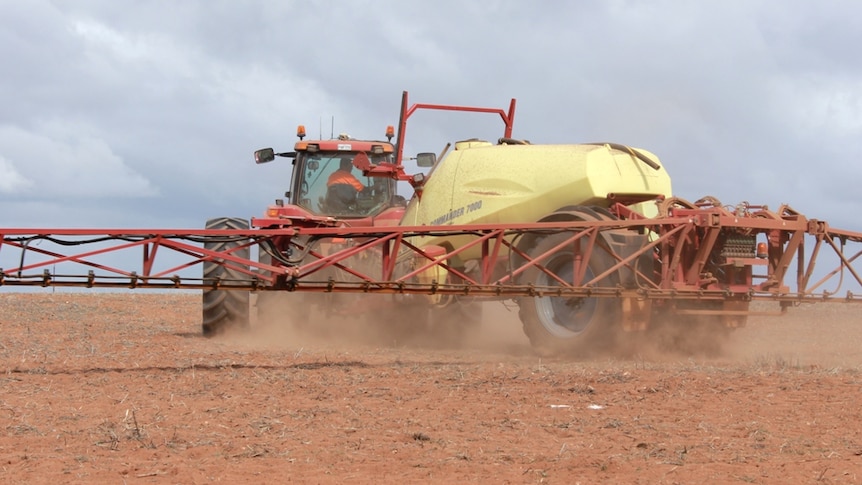 A large harvesting machine at work in a paddock on a sunny day