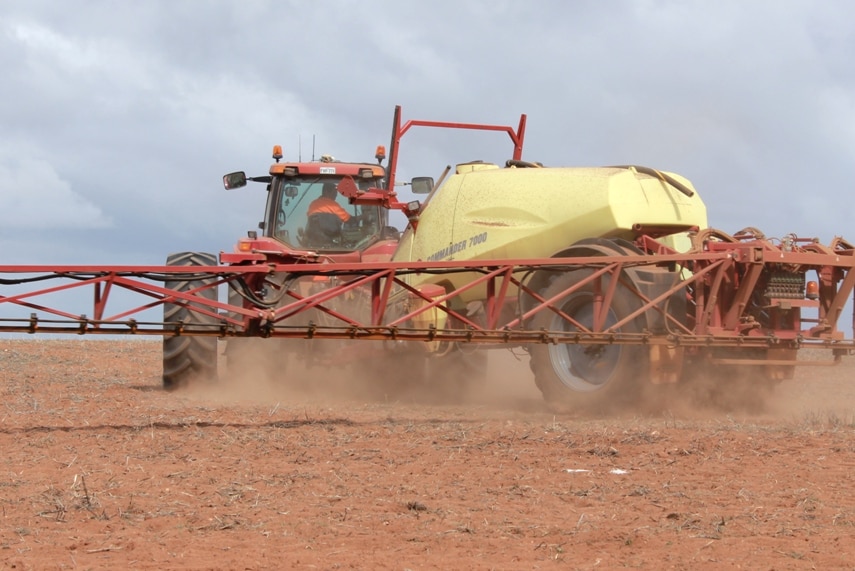A large harvesting machine at work in a paddock on a sunny day