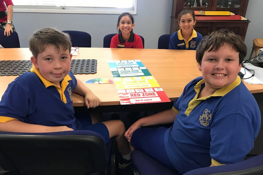 Four kids sit around a table smiling