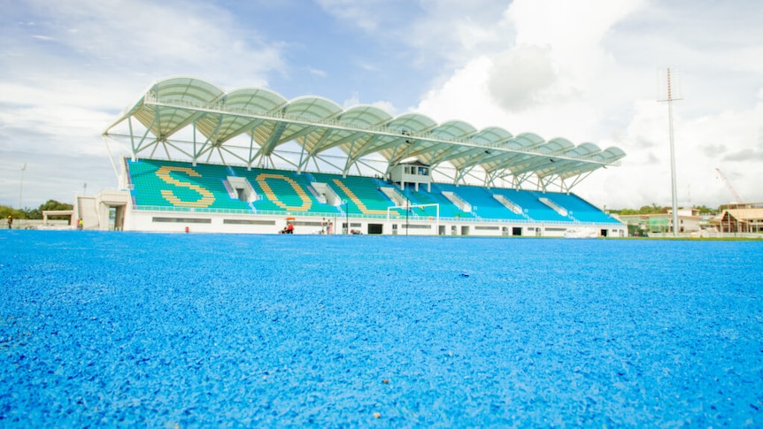 Bright blue floor of a brand new stadium with white roof. Letters S O and L can be read on seating