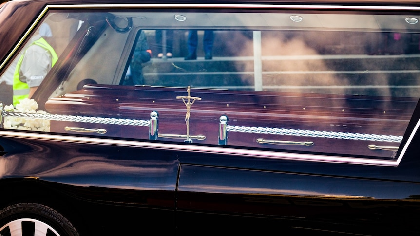A coffin can be seen through the window of a hearse