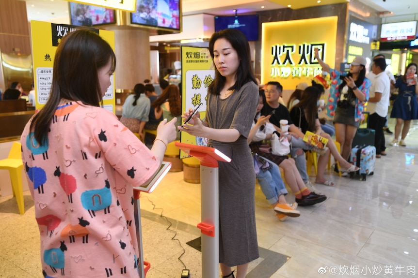 A customer is weighed before heading into a restaurant in China.