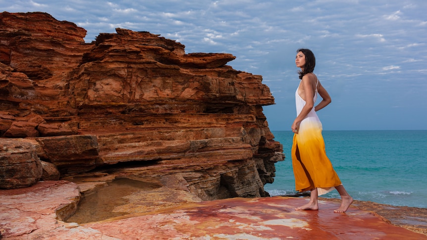 Lady in dress at rocks by ocean