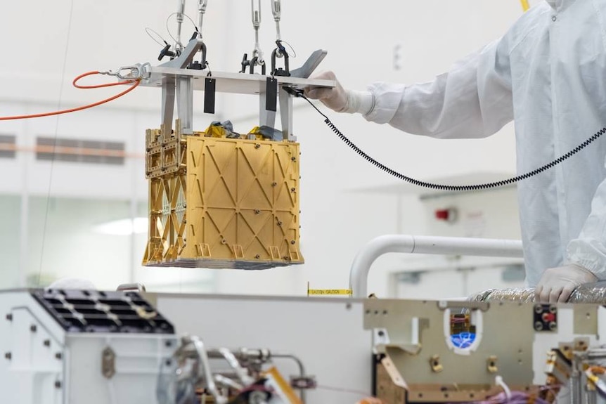 Technicians at NASA's Jet Propulsion Laboratory holding the Mars Oxygen In-Situ Resource Utilization Experiment instrument
