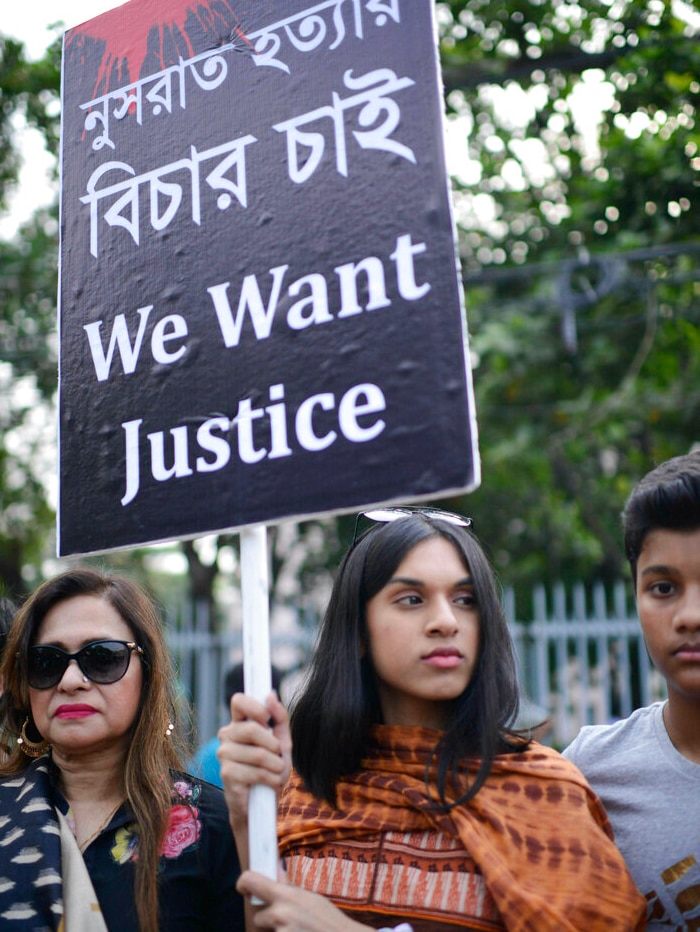 A young woman holds up a black sign that says "we want justice"