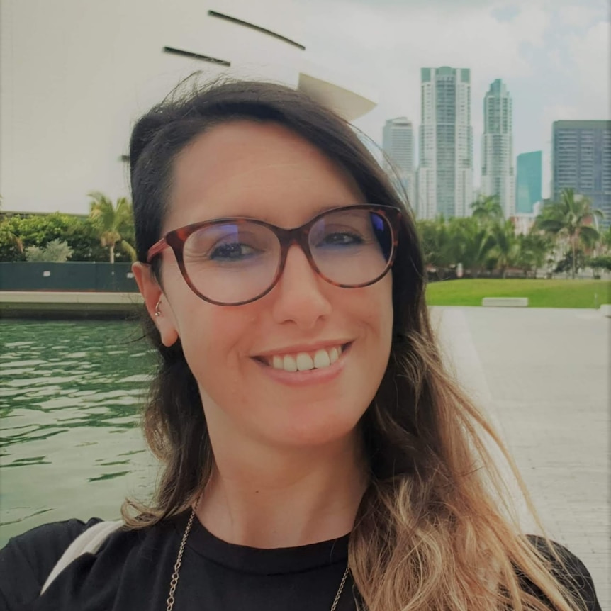 A woman smiles in front of a river