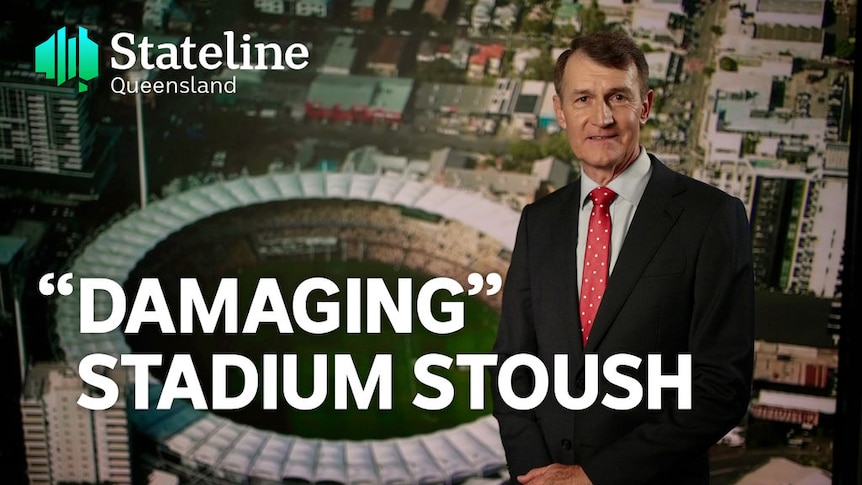 'Damaging' Stadium Stoush:Man in suit stands infront of aerial picture of Gabba stadium om Brisbane.