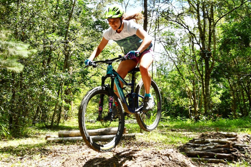 A woman racing through bushland on a mountain bike.