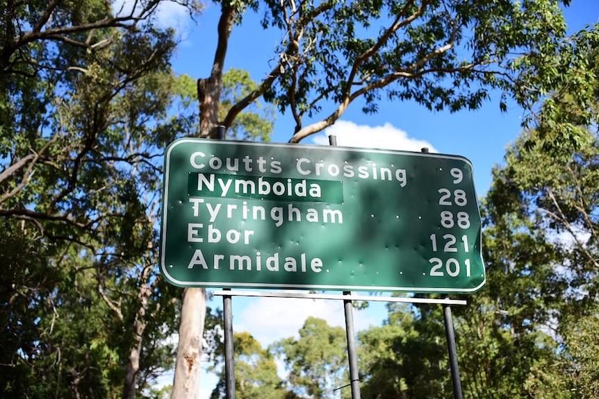 A green and white  road sign with numerous towns and kilometres on it.