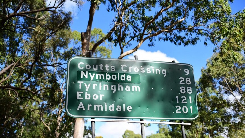 A green and white  road sign with numerous towns and kilometres on it.