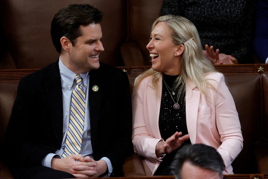 A man and woman laugh together in congress. 