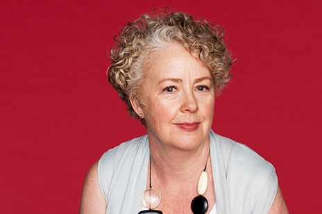 a woman in front of a red background looking into camera