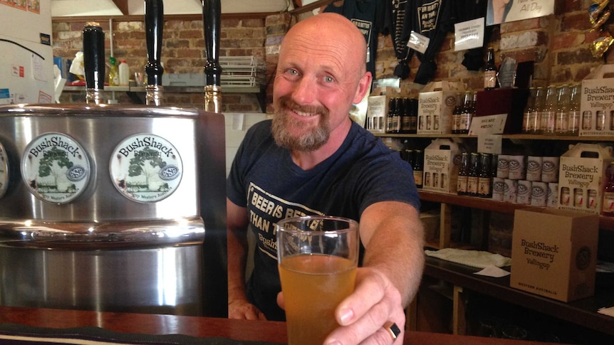 brewer Daniel Wind leans over the bar with a glass of beer.