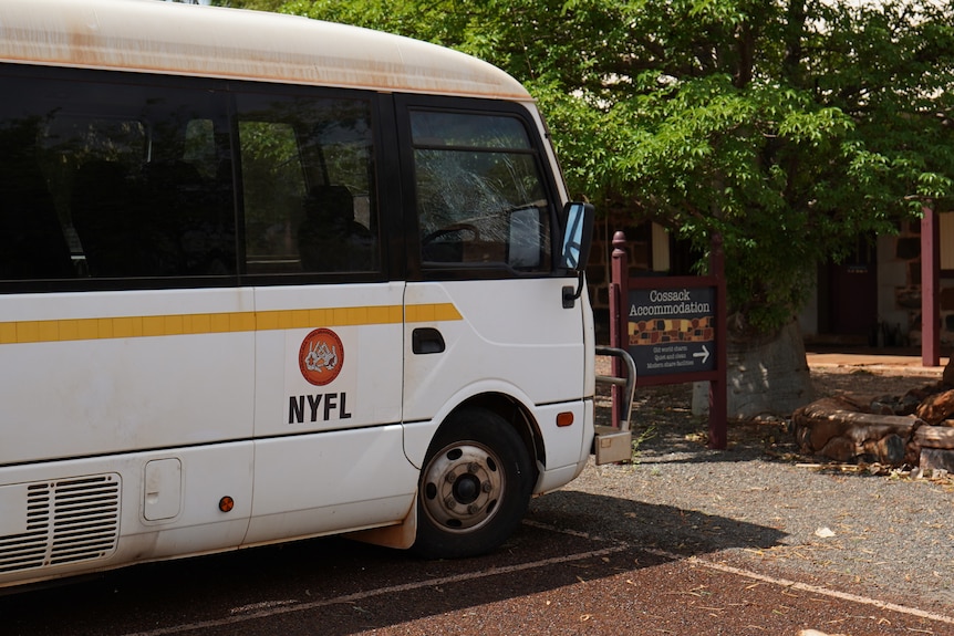 A white bus with an orange logo and the letters: NYFL parked outside an accomodation building in Cossack.