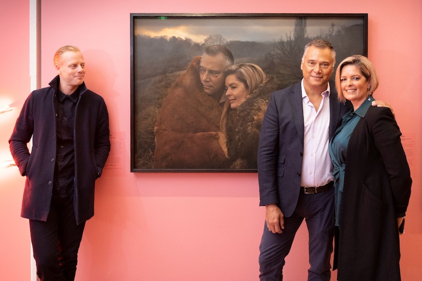 Journalists Stan Grant and Tracey Holmes stand in front of a portrait of themselves. The photographer stands off to the side.