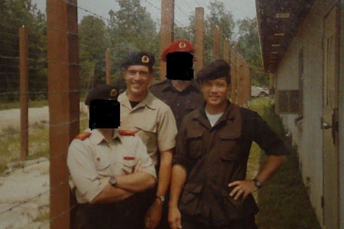 An old photo of four soldiers, two with their faces blacked out 