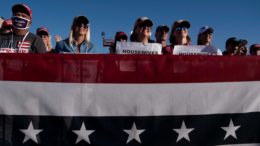 Trump supporters stand in front of American flag listening at yesterday's rally led by President Donald Trump