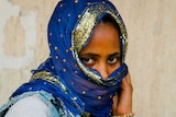 A woman in a blue and gold scarf wrapped around her face