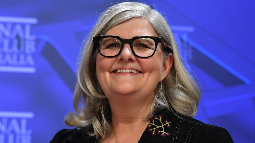 A woman wearing glasses and smiling.