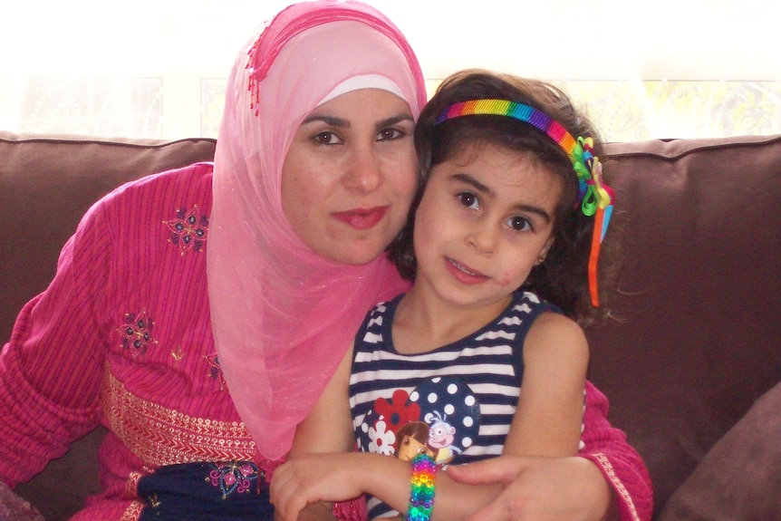 A woman wears a face veil hugging her daughter.