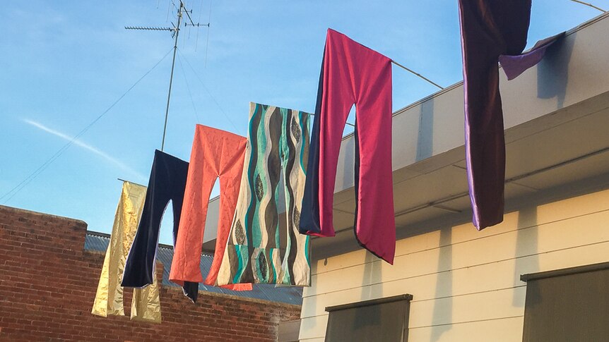 Flared pants hanging from poles from a roof