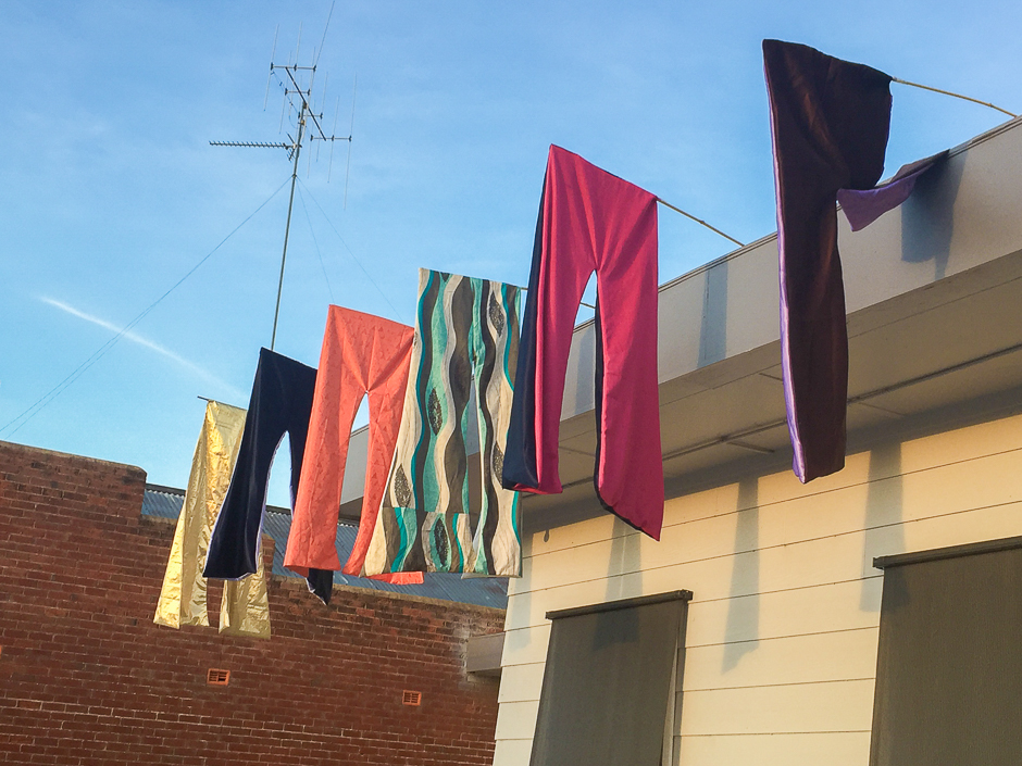 Flared pants hanging from poles from a roof