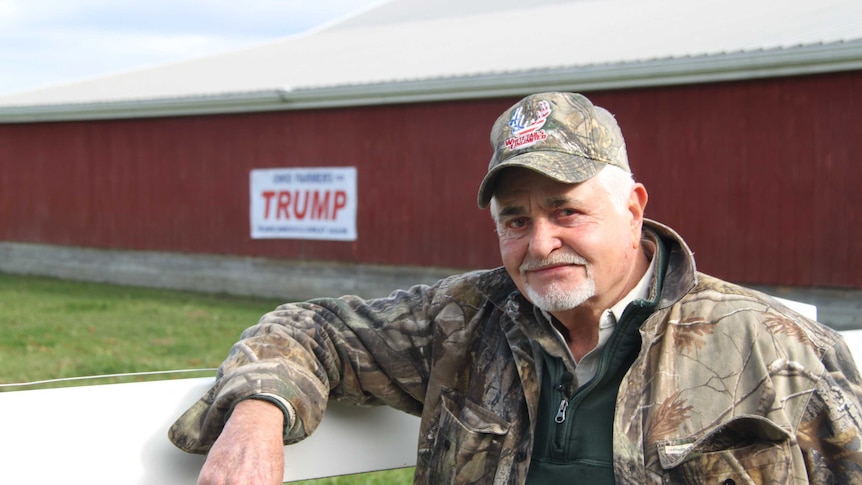 Dominic Marchese leans on a fence in front of his barn, which carries a campaign sign for Donald Trump.