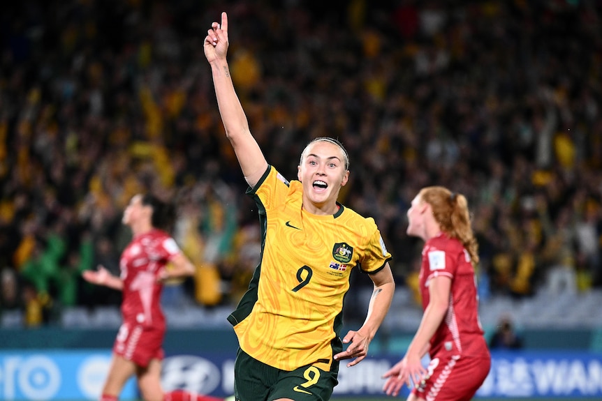 Footballer Caitlin Foord running in celebration, finger in the air, after socring for her country