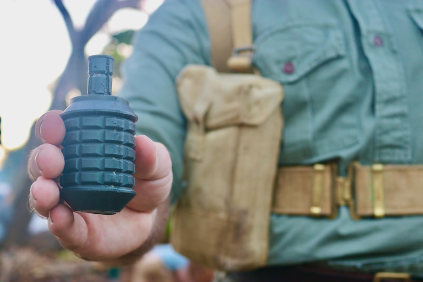Reenactment photo of a man in uniform holding a grenade.