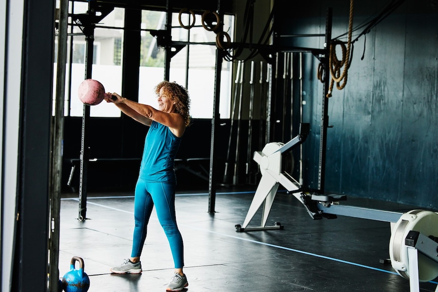 A woman doing kettlebell swings during workout in gym