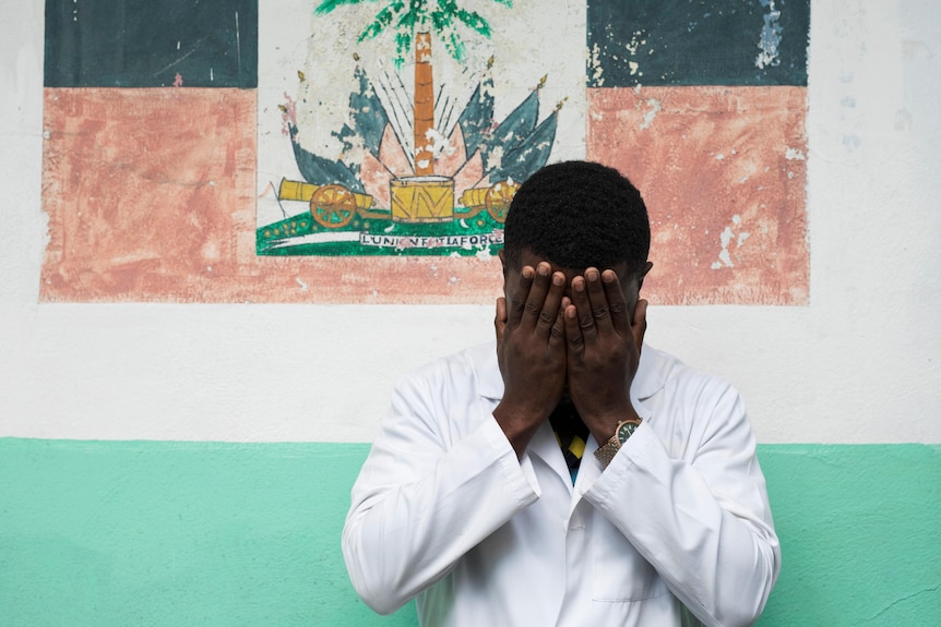 A Haitian doctor who was abducted from his hospital covers his hands with his face to maintain anonymity in this March photo.