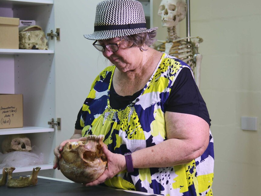 A woman holds and examines a human skull.