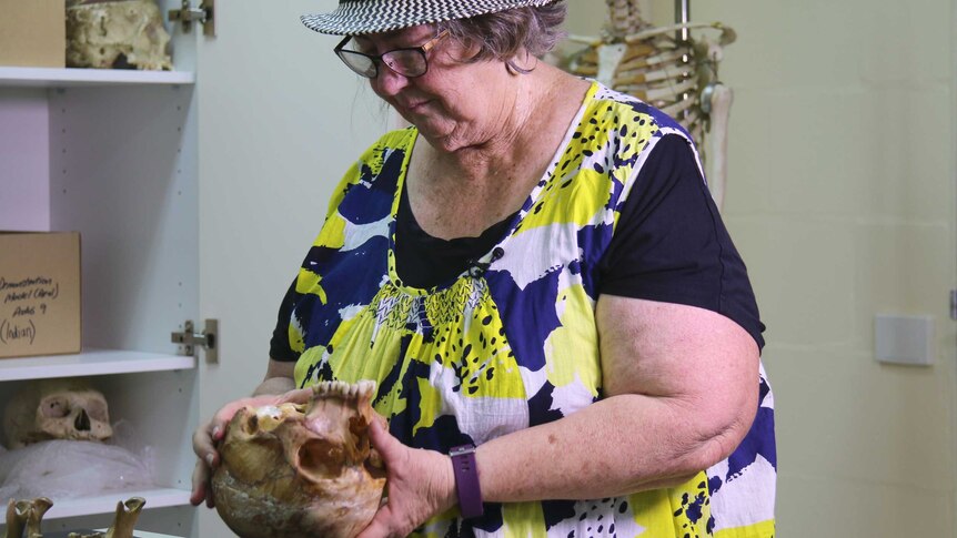 A woman holds and examines a human skull.