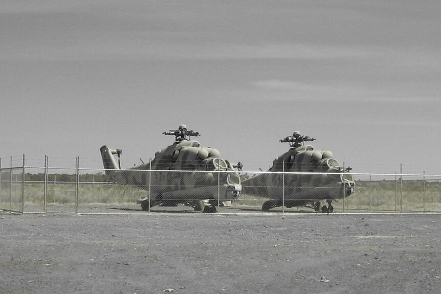 A black and white photo of two Mil Mi-24 Hind attack helicopters on the ground.