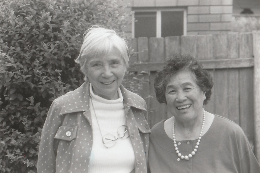 A black and white photo of two older women of Chinese heritage smiling. 