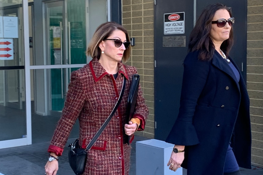 Two smartly dressed women wearing sunglasses walk outside Fremantle Court.