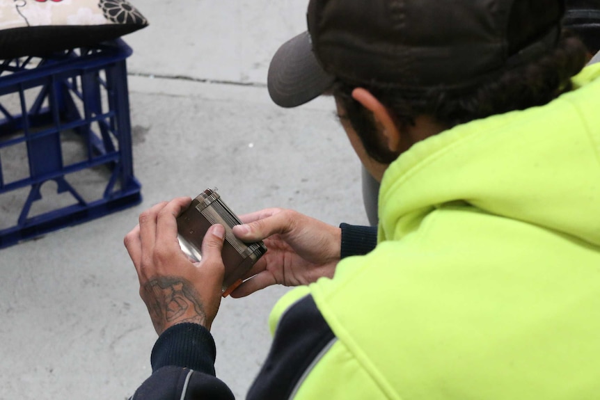 Mark Brown's hands hold a tool, the photo taken over his shoulder.