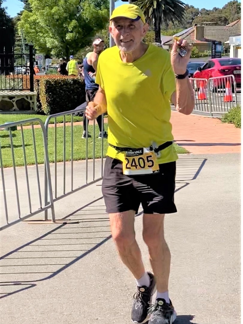 Steve Connelly, dressed in yellow and with the ID number 2405, approaches the finish line of a half marathon