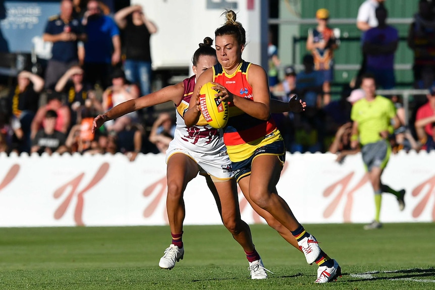 Ebony Marinoff controls the ball for the Adelaide Crows while in front of a Brisbane Lions opponent.