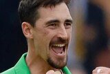 Mitchell Starc clenches both his fists and opens his mouth in a wide smile