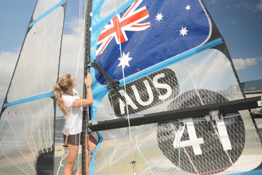 Female sailor Jaime Ryan hoists a sail bearing the Australian flag