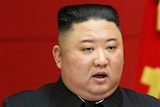Kim Jong Un in front of a red background.