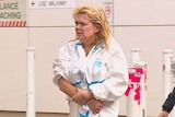 A woman in a prison suit walks between two officers.
