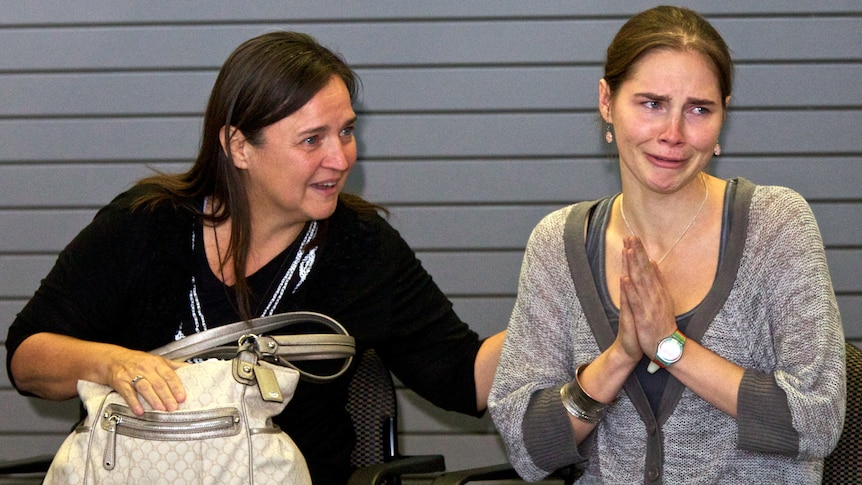 Amanda Knox acknowledges the cheers of supporters while her mother Edda Mellas comforts her