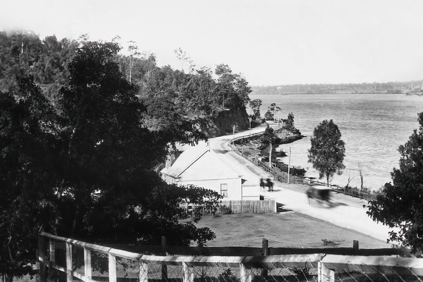 A road that runs along the Brisbane River and wraps around a curve of a hill.